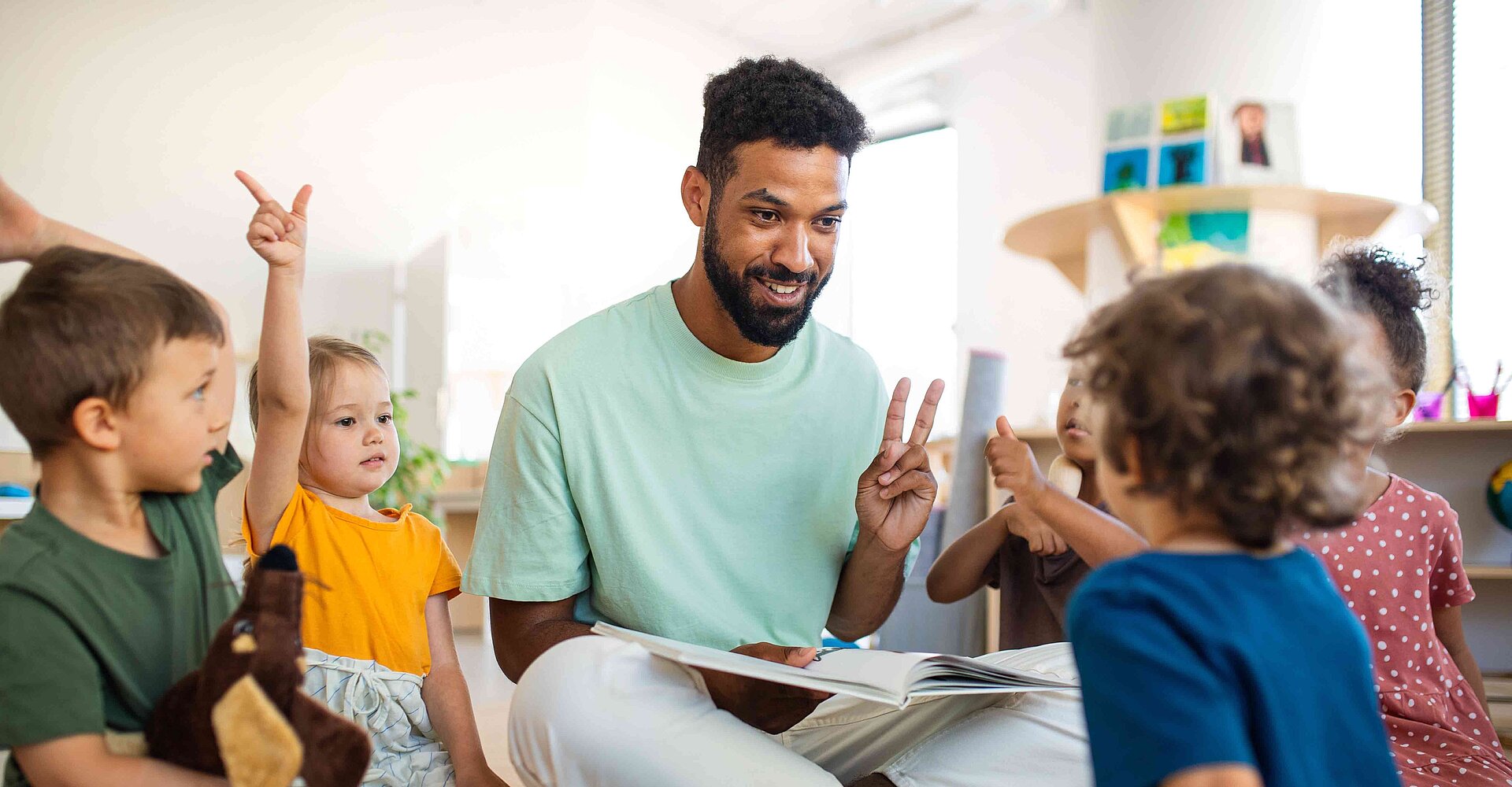 Ein Erzieher spielt mit Kindergarten auf dem Boden mit Kindern.
