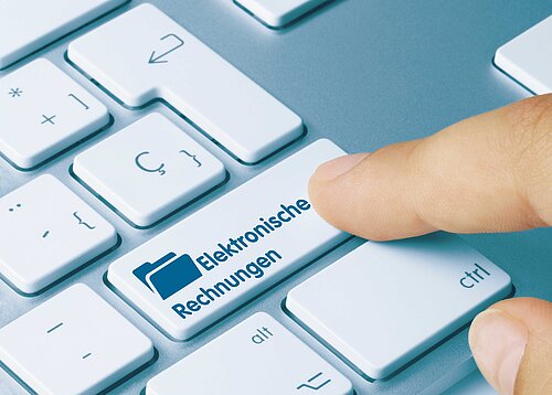 Ein Zeigefinger einer Person zeigt auf eine Taste auf einer Tastatur.