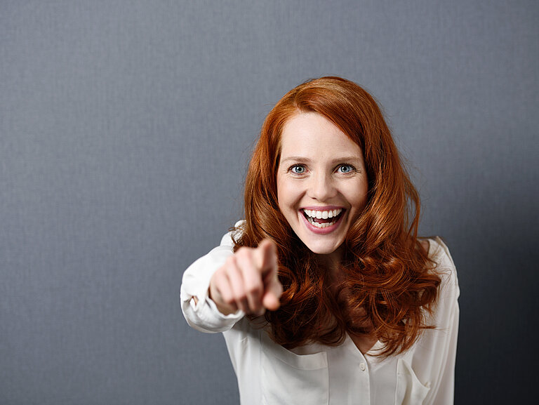 lachende frau zeigt mit dem finger nach vorne