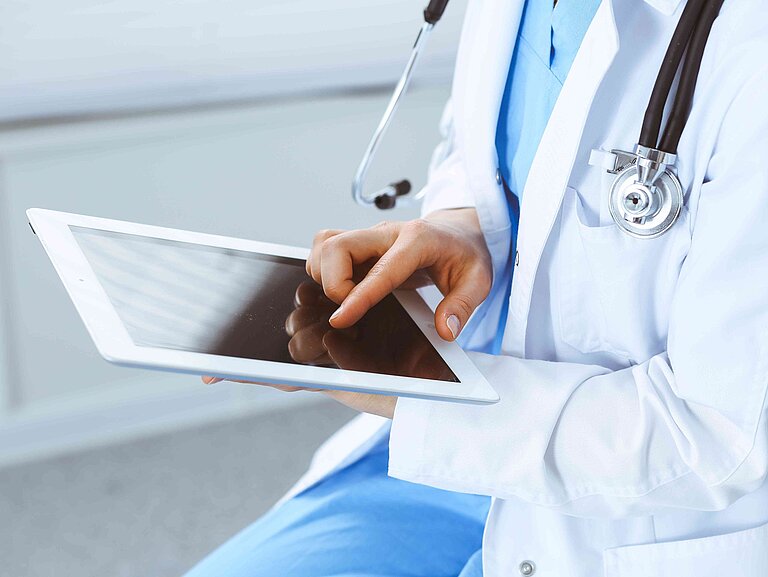 Eine Arzt tippt auf einem Tablet.