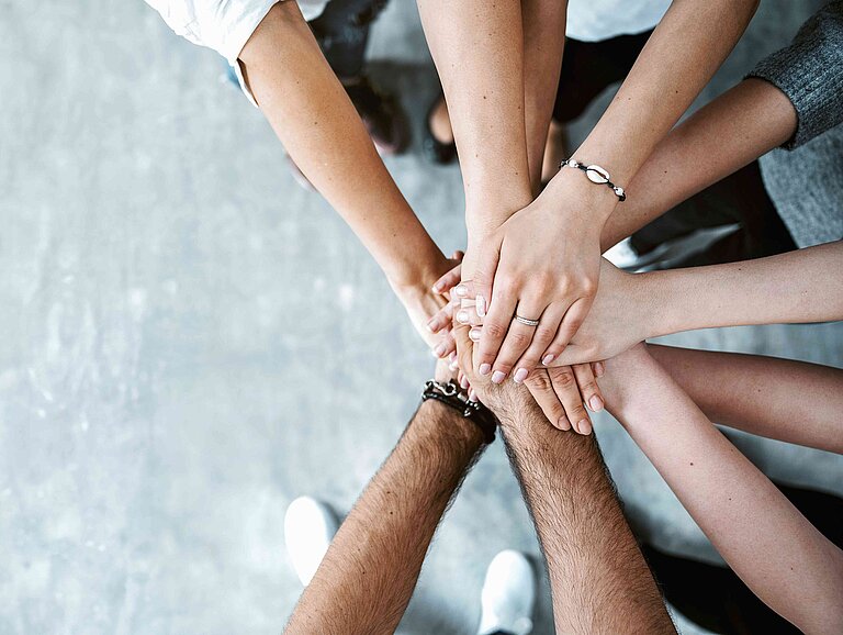 Viele Hände übereinander als Symbol des Zusammenhaltes