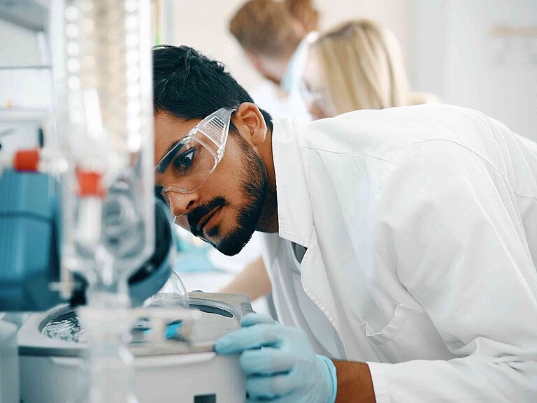 Ein Mann mit Schutzbrille ist im Labor, trägt eine Schutzbrille und untersucht eine Flüssigkeit.