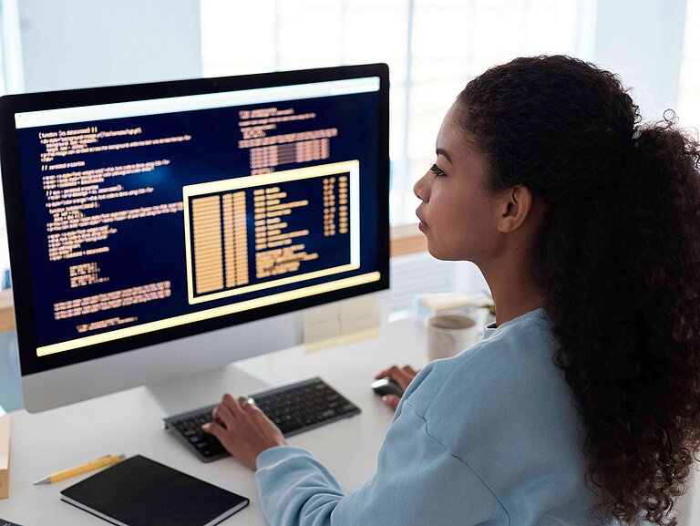 Eine Frau sitzt an einem Schreibtisch und arbeitet an einem Computer.