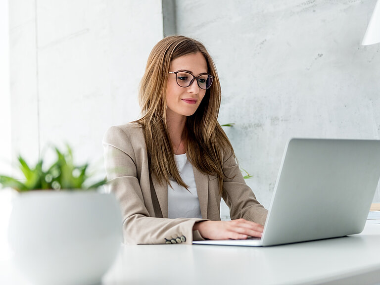 Frau in Businessoutfit sitzend am Laptop