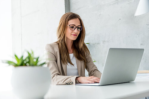 Frau in Businessoutfit sitzend am Laptop
