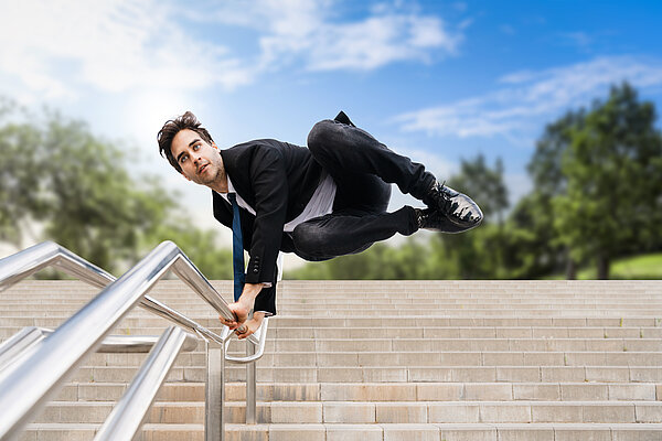 Mann gleitet an einem Handlauf übertrieben die Treppe runter