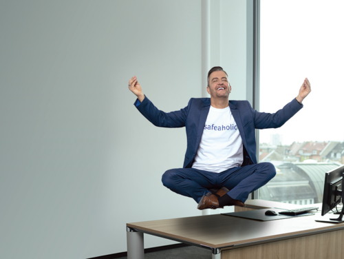 Ein Mann schwebt im Schneidersitz über einem Schreibtisch. Den Kopf hat er leicht nach oben geneigt, die Augen sind geschlossen und die Hände streckt er in die Höhe.