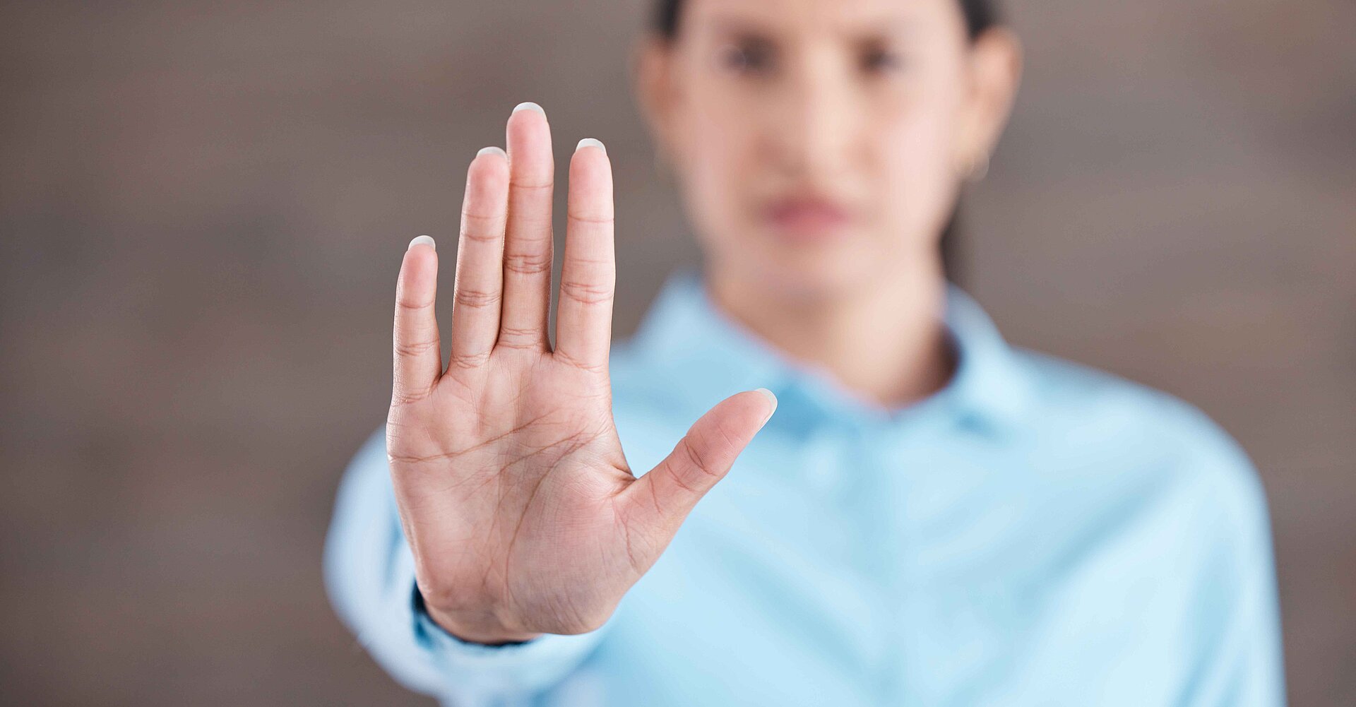 Frau schaut nach vorne und hebt die Rechte Hand schützend nach vorne.