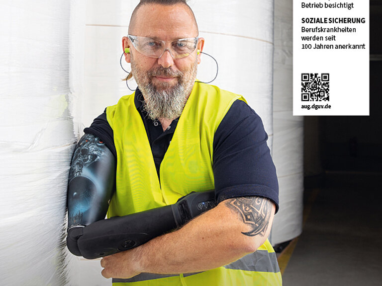 Titelbild Arbeit und Gesundheit. Mann lehnt mit Arbeitsweste bekleidet an einer Wand und schaut in die Kamera. Portraitaufnahme.