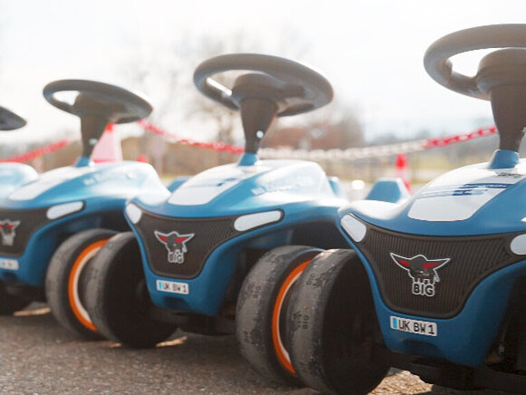 mehrere blaue Rutschauto stehen nebeneinander auf einem asphaltierten Platz.
